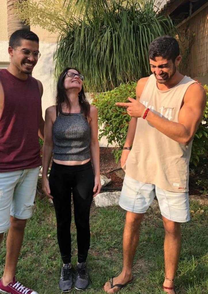 Ziv Hagbi laughing with family in a sunlit garden, pointing playfully as others smile with him