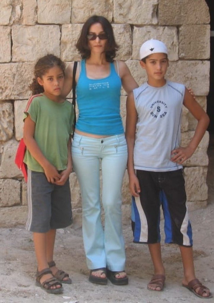 A childhood photo of Ziv Hagbi with family standing before an ancient stone wall