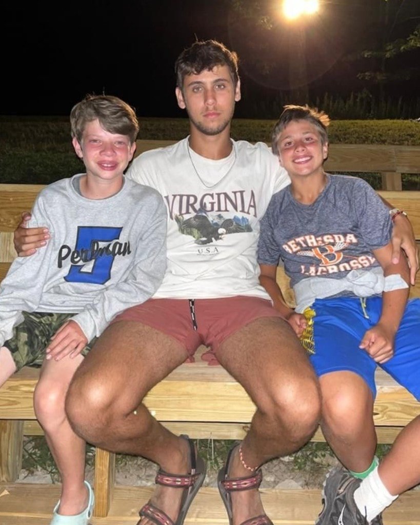 Ron Shemer sitting on a wooden bench at night between two younger boys