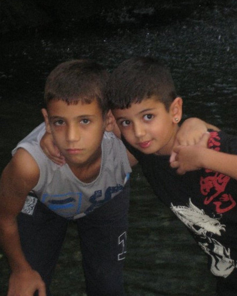 Two young boys posing with their arms around each other's shoulders